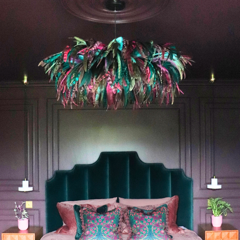 Decorative chandelier hanging above a bed with floral bedding in a darkly decorated room.