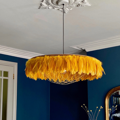 Yellow feather lampshade. Feather light shade on a stiffkey blue wall